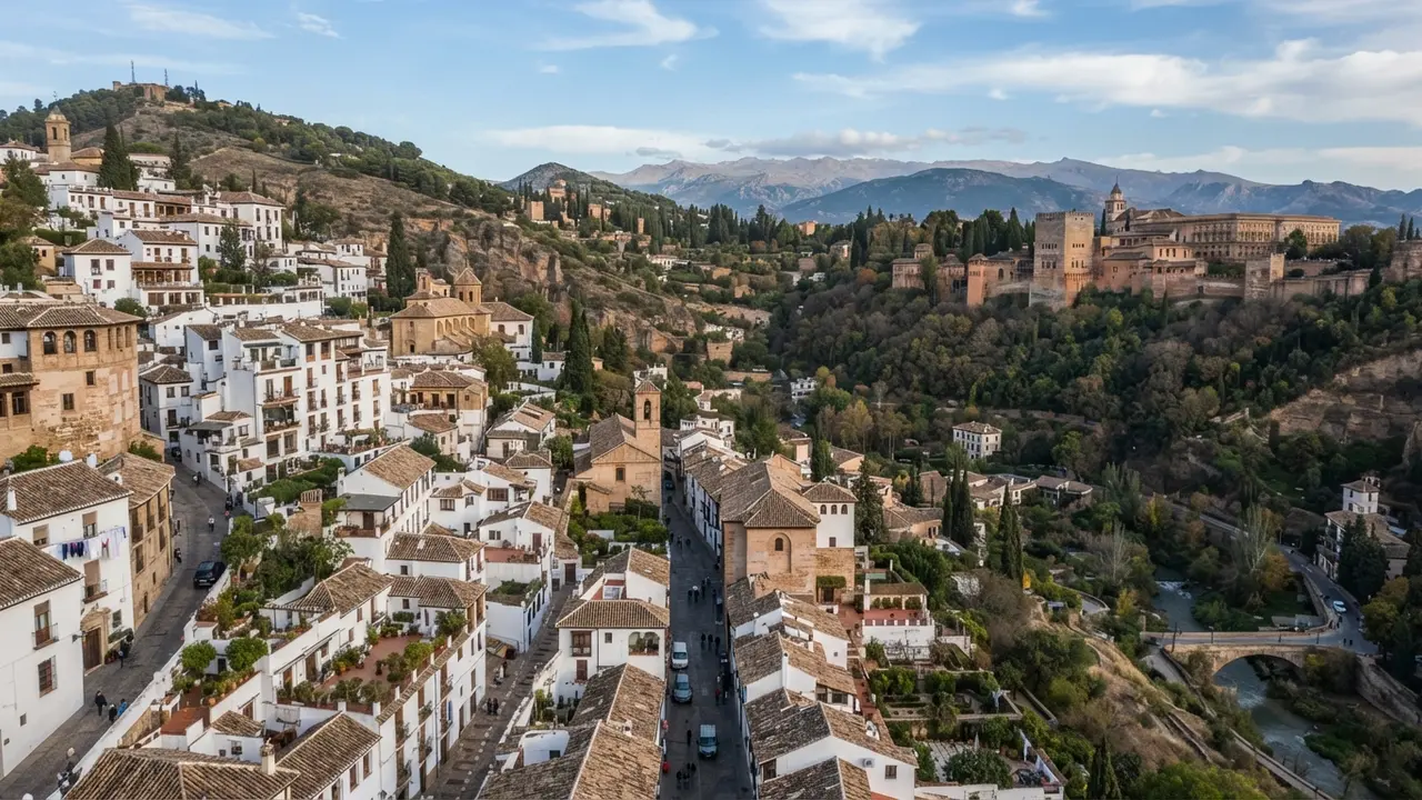 Aerial view of Granada's Albaicín hillside with whitewashed houses and the Alhambra on the facing ridge